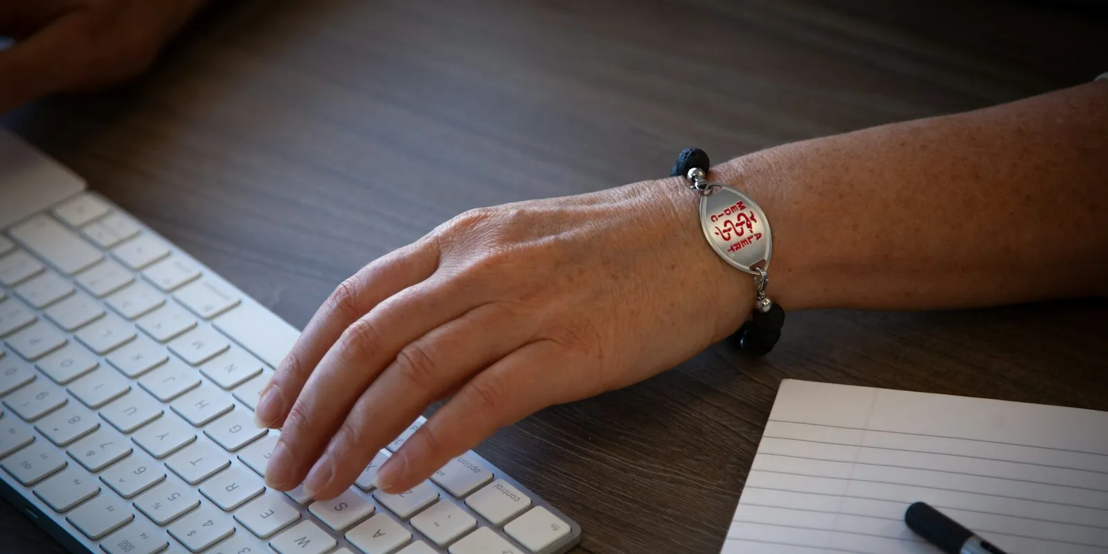 Main et poignet posés au bureau devant un clavier